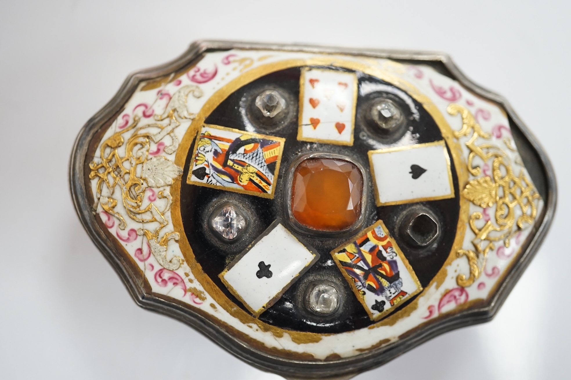 A continental white metal, enamel and two colour paste? set shaped oval snuff box, decorated with playing cards, unmarked, 67mm. Condition - poor